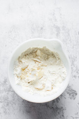 butter and flour being mixed together in a white bowl, butter and flour mixed into rough pastry, butter and flour being use to make cookie dough or pie dough, process of making cut out sugar cookies