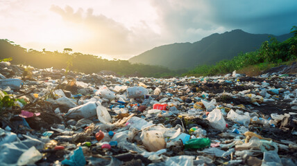Plastic trash on the ground with mountains in the background at sunset