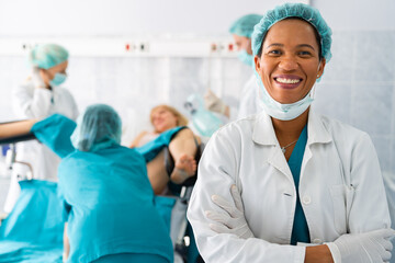 Portrait of successful smiling African American female doctor gynecologist with surgical cap and...