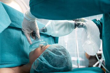 Female patient receiving anesthesia during surgery while lying on operating table in operating...
