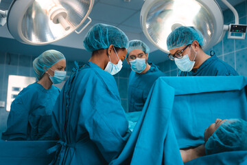 Professional medical team of concerted serious surgeons wearing operating gowns performing chest...