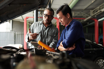 Car mechanic talking to owner, showing him results of diagnostics