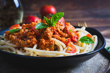 Spaghetti pasta and tomato sauce with chicken mince on a wooden background. Pasta bolognese.