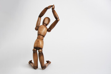 Wooden mannequin pose of praying man, kneeling and raising his hands up.