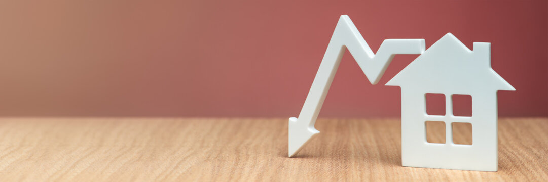 Decrease in property value. Reducing the cost of housing. Banner with a model of a white house and a graphic arrow pointing down close-up on a red background. copy space.