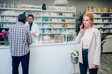 Obraz premium Portrait of a woman customer in a pharmacy using a smartphone