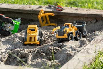 excavator and children toy truck in a sandbox