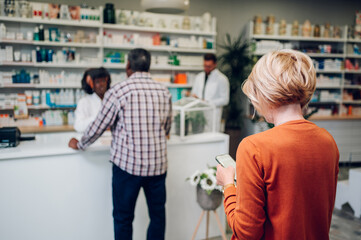 A queue of people standing in a pharmacy while shopping for medicine
