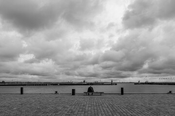 Black and white tone, outdoor exterior view, lonely mood of one old man sit on the bench on the...