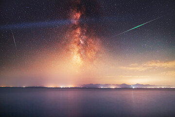 Beautiful night landscape,  bright Milky Way galaxy and meteors on the lake.