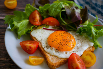 Bread with fried egg, tomatoes, lettuce