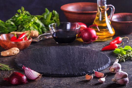 Culinary background with kitchen slate stone serving platter, olive oil and vegetables. Selective focus with copy space for text