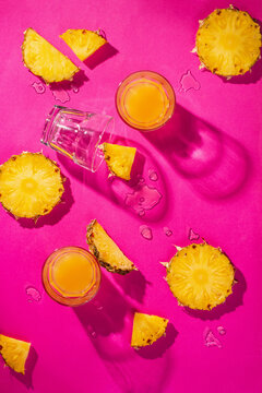 Pineapple pieces and pineapple juice isolated on pink background. Tropical holiday concept. Flat lay, top view