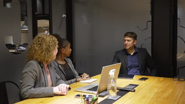 interracial group of three business people in meeting room discussing conversing planning