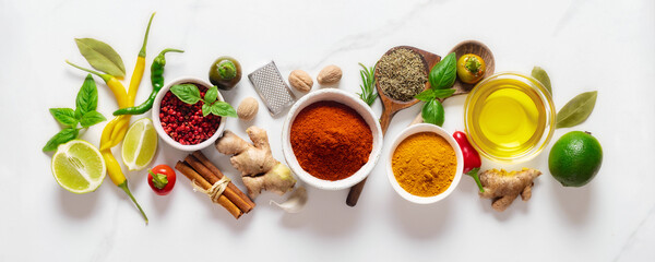 Food cooking ingredients background with various herbs, spices and olive oil on white marble...