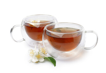 Glass cups of tea and beautiful jasmine flowers on white background