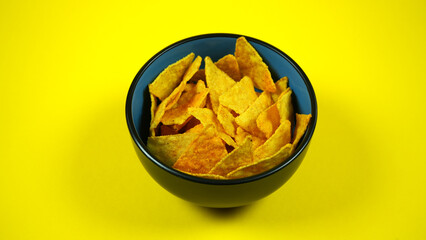 Close-up of corn chips or tortilla in bowl against yellow background. Mexican Corn Chips Nachos on yellow background. Top view. Copy space