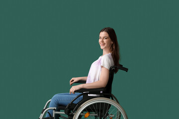 Obraz na płótnie Canvas Young woman in wheelchair on green background