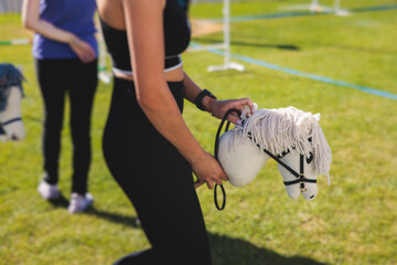 Hobby horsing competition on a green grass, hobby horse riders jumping, equestrian sport training...