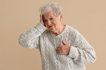 Elderly woman having heart attack on beige background