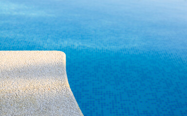 Empty pool edge with blue calm water. Selective focus on the edge of the pool. The concept of relaxing holidays and spa treatments. Free space