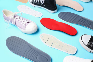 Composition with different orthopedic insoles and shoes on color background