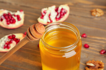 Jar of honey with pomegranate and walnut for Rosh Hashanah celebration (Jewish New Year) on wooden table