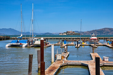 Piers with boats docked and distant Alcatraz Island on bright sunny day with clear blue skies