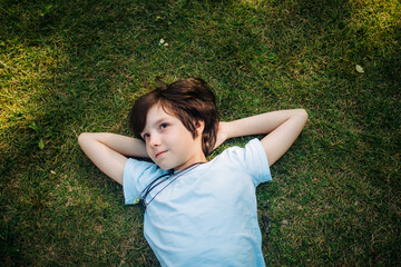 Smiling boy lying down with hands behind head on grass