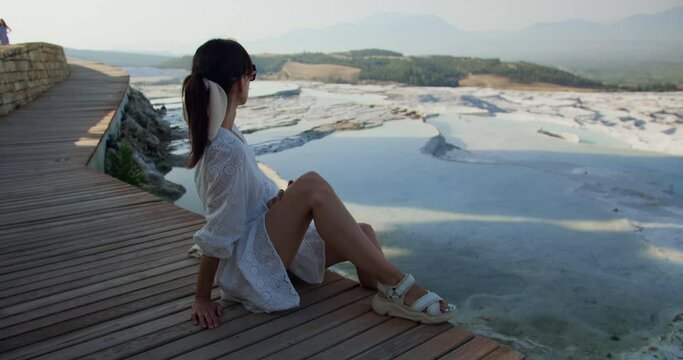 Young woman sitting near travertine pools limestone terraces in Pamukkale, Denizli