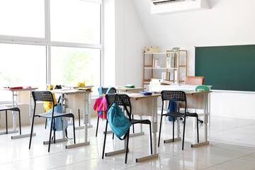 Interior of modern classroom with desks and chairs at school