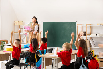 Little school children with teacher in classroom during lesson