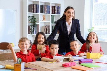 Female teacher with little school children in classroom