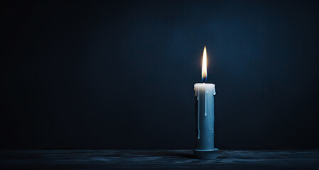 A single candle stands alone against a backdrop of deep blue, creating a tranquil and contemplative scene