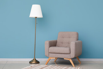 Cozy grey armchair and standard lamp near blue wall