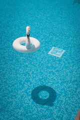Inflatable swan pool float in a mosaic-tiled swimming pool