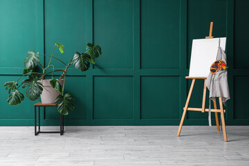 Wooden easel with blank canvas near green wall