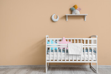 Interior of children's room with crib near beige wall