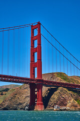 Close up of Golden Gate Bridge with bright blue sky and choppy bay waters