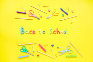 Text BACK TO SCHOOL and stationery on yellow background