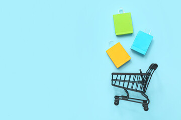 Small shopping cart with bags on blue background