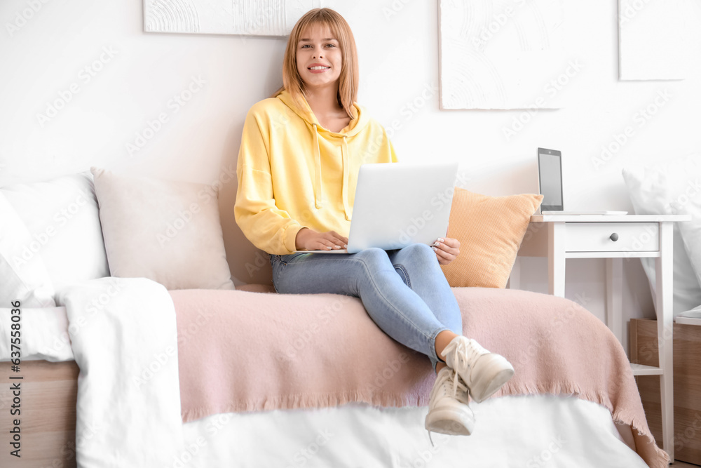 Wall mural Female student studying with laptop in dorm room