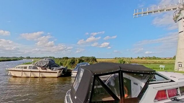 Thurne mill and motorboats moored up on the River Thurne in the heart of the Norfolk Broads National Park.  Captured on a bright and sunny summer evening