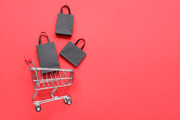 Shopping cart with bags on red background. Black Friday concept