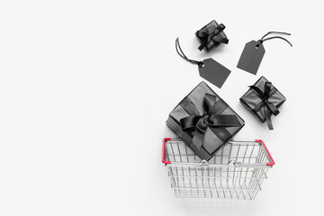 Shopping basket with gift boxes on white background. Black Friday concept