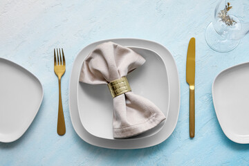 Elegant table setting with golden cutlery and napkin on light blue table