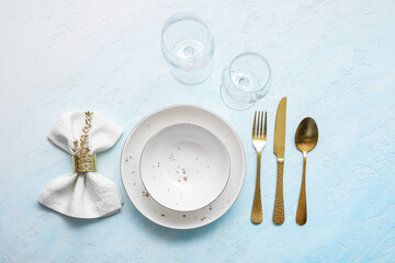 Elegant table setting with golden cutlery and napkin on light blue table