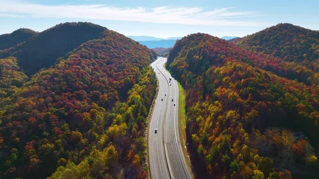 I-40 freeway road leading to Asheville in North Carolina thru Appalachian mountains with yellow fall forest and fast moving trucks and cars. Concept of high speed interstate transportation