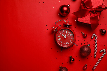 Alarm clock with Christmas decor on red background