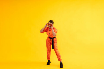 Fototapeta na wymiar Full length body size photo of happy woman wear modern Orange overalls on bright yellow color background. Cheerful and energetic middle age female with colored make up having fun near copy space